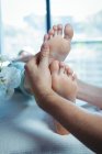 Imagen recortada de fisioterapeuta masculino dando masaje de pies a paciente femenina en clínica - foto de stock
