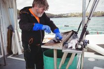 Senior Fisherman filleting fish in boat — Stock Photo