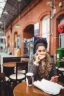 Mujer comiendo mientras está sentada en un restaurante en la estación de tren - foto de stock