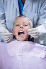 Вивчаючи молоді пацієнта з інструментами на Стоматологічна клініка стоматолог — стокове фото