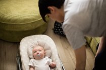 Mother looking at her baby in stroller at home — Stock Photo