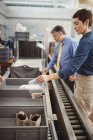 Пасажир вставляє пластиковий пакет у лоток для перевірки безпеки в аеропорту — стокове фото