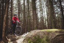 Горный велосипедист с велосипедом среди деревьев в лесу — стоковое фото