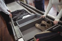 Woman putting shoes into tray for security check at airport — Stock Photo