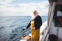 Fisherman looking at sea from fishing boat — Stock Photo