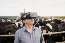 Agricultor utilizando simulador de realidad virtual por valla contra el cielo - foto de stock
