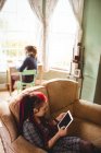 Junge Frau hält digitales Tablet mit Mann am Fenster zu Hause — Stockfoto
