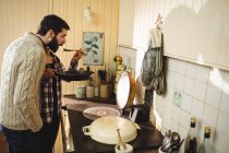 Мужчина дегустирует пищу, приготовленную женщиной на кухне — стоковое фото