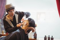 Man getting his beard shaved with razor in barber shop — Stock Photo