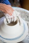 Обрезанный образ горшечника, делающего горшок в керамической мастерской — стоковое фото