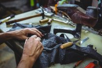 Mani di calzolaio tagliare un pezzo di materiale in officina — Foto stock