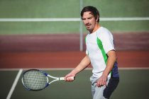 Зрелый мужчина играет в теннис на спортивном корте — стоковое фото