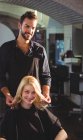Guapo peluquero con cliente en peluquería — Stock Photo