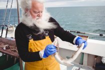 Capelli grigi Pescatore che tiene i pesci sulla barca — Foto stock