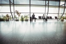 Uomini d'affari seduti con i bagagli in sala d'attesa nel terminal dell'aeroporto — Foto stock