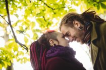 Романтическая пара хипстеров смотрит друг на друга, стоя в парке — стоковое фото