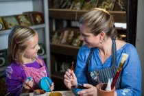 Töpferin hilft Mädchen beim Malen in Töpferwerkstatt — Stockfoto