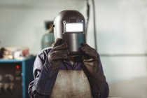 Soldador segurando capacete de soldagem na oficina — Fotografia de Stock