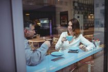 Hombre y mujer tomando café en la cafetería - foto de stock