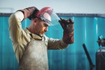 Мужчина-сварщик в защитном шлеме в мастерской — стоковое фото