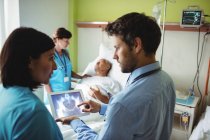 Мужчина врач и медсестра смотрят на цифровой планшет в больнице — стоковое фото