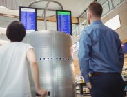 Viajantes olhando para as placas de tela de partida e chegada exibe no aeroporto — Fotografia de Stock
