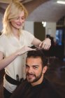 Coiffeur coupe les cheveux du client au salon de coiffure — Photo de stock