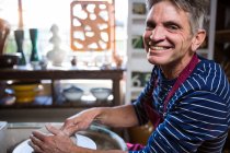 Портрет щасливого чоловіка-гончаря, який робить горщик у керамічній майстерні — стокове фото