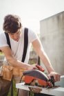 Carpenter cutting wooden frame from circular saw in lawn — Stock Photo