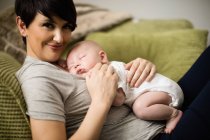 Close-up of baby sleeping on mother in living room at home — Stock Photo