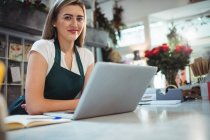 Female florist standing with laptop in the flower shop — Stock Photo