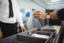 Passenger putting plastic bag into tray for security check at airport — Stock Photo