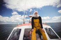 Thoughtful fisherman sitting on deck and looking away — Stock Photo