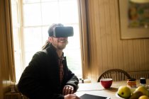 Jovem sorridente usando simulador de realidade virtual em casa — Fotografia de Stock