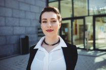 Portrait of smiling young businesswoman against building — Stock Photo