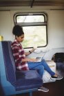 Повна довжина молодої жінки, використовуючи ноутбук, сидячи в поїзді — стокове фото