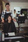 Улыбающаяся женщина-парикмахер работает с клиентом в парикмахерской — стоковое фото