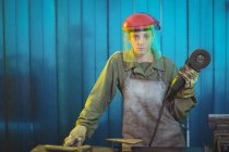 Portrait of female welder holding circular saw in workshop — Stock Photo