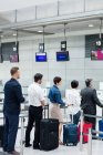 Passengers waiting in queue at a check-in counter with luggage inside the airport terminal — Stock Photo
