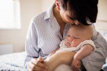 Madre besando su cabeza de bebé en casa - foto de stock