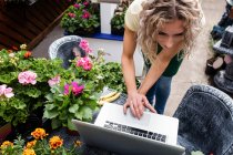 Florista feminina usando laptop no centro de jardim — Fotografia de Stock