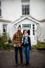 Retrato de casal em pé perto de uma nova casa com os braços ao redor — Fotografia de Stock