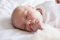 Adorável bebê dormindo na cama com ursinho de pelúcia em casa — Fotografia de Stock