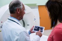 Médico explicando al paciente sobre la resonancia magnética cerebral en tableta digital en el hospital - foto de stock