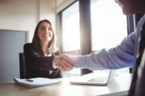 Cropped image of Businesswoman shaking hands with colleague in office — Stock Photo