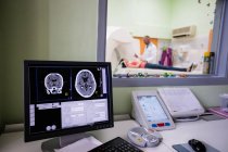 Exploración cerebral digital en el monitor de la computadora con escáner de resonancia magnética en segundo plano - foto de stock