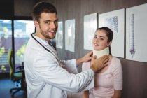Retrato de fisioterapeuta examinando paciente mujer cuello en clínica - foto de stock