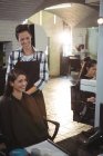 Sorrindo cabeleireiro feminino trabalhando no cliente no salão de cabeleireiro — Fotografia de Stock