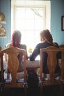 Вид ззаду молода пара сидить за столом вдома — стокове фото