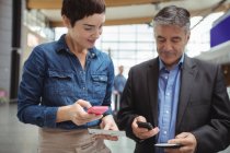 Business people holding boarding pass and using mobile phone in airport terminal — Stock Photo